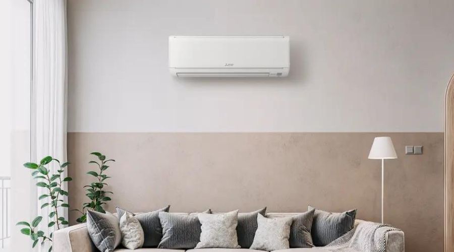 Ductless mini-split air conditioning unit mounted on a wall above a modern sofa in a stylish living room, showcasing efficient heating and cooling solutions for improved indoor air quality.