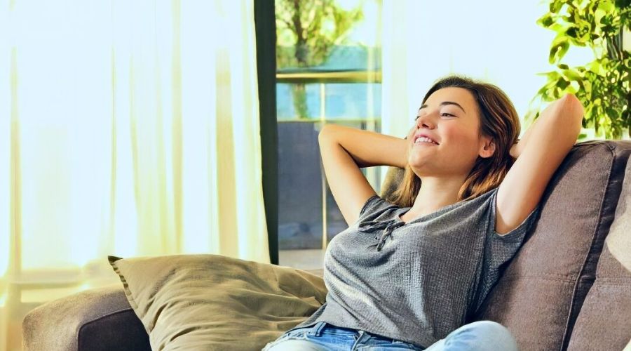Relaxed woman enjoying a cool indoor environment, emphasizing comfort and tranquility in a well-lit living space.